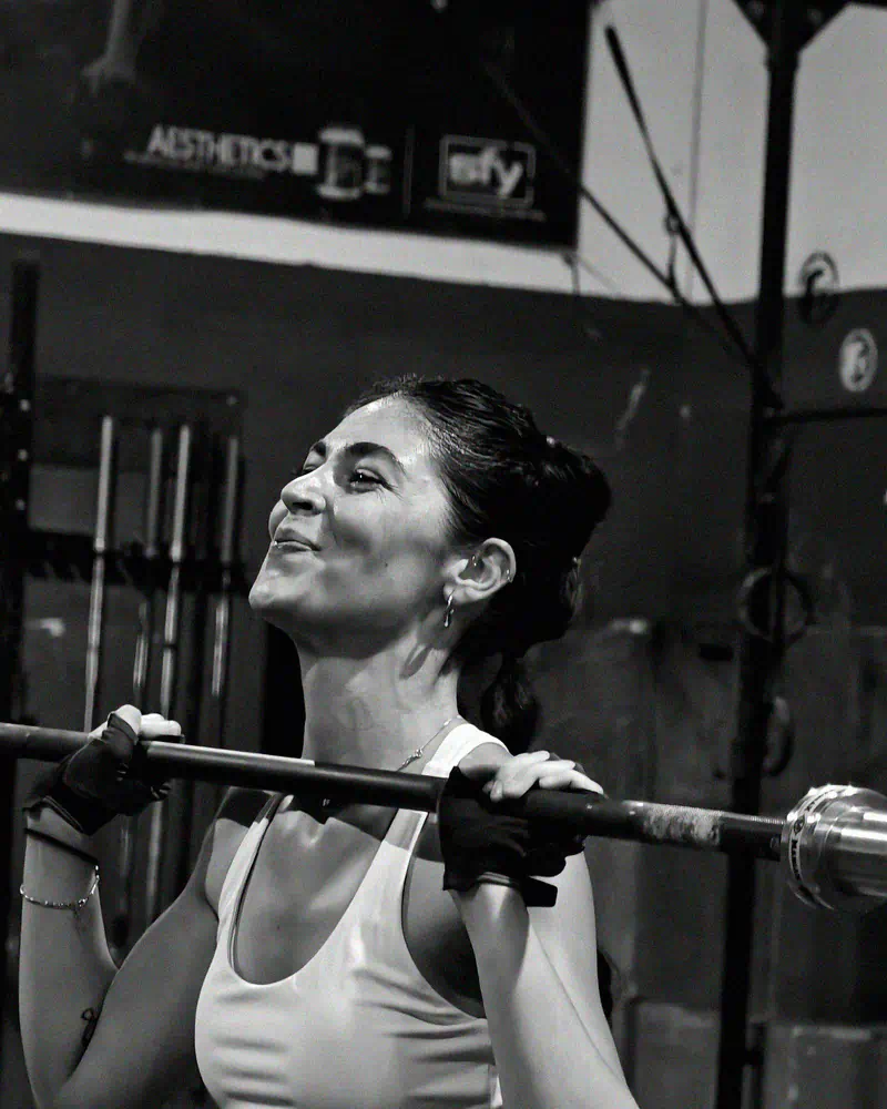 Socia sonriendo mientras sujeta la barra en posición de rack